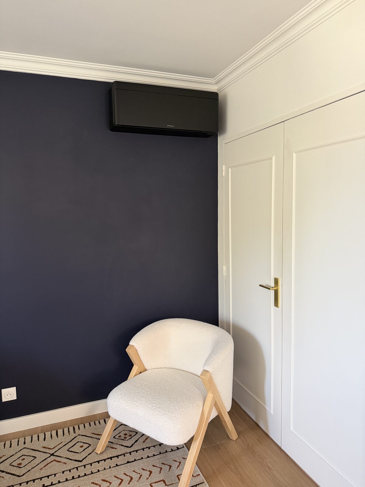 Climatiseur Daikin Stylish noir installé dans une chambre au mur bleu nuit, finition haut de gamme
